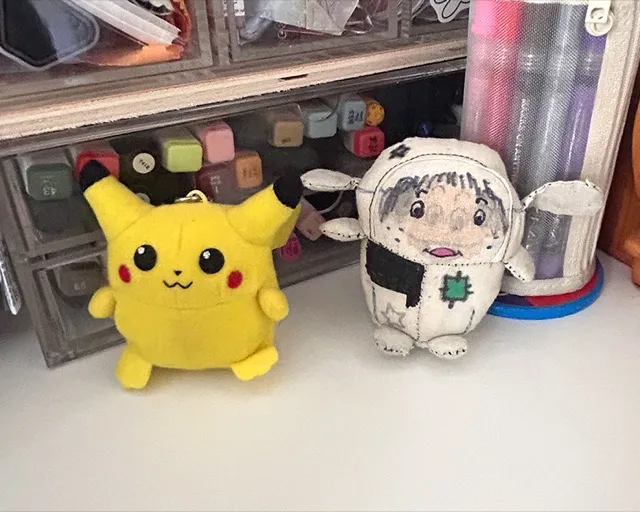 a pikachu keyring and the plushie creature next to each other for comparision.